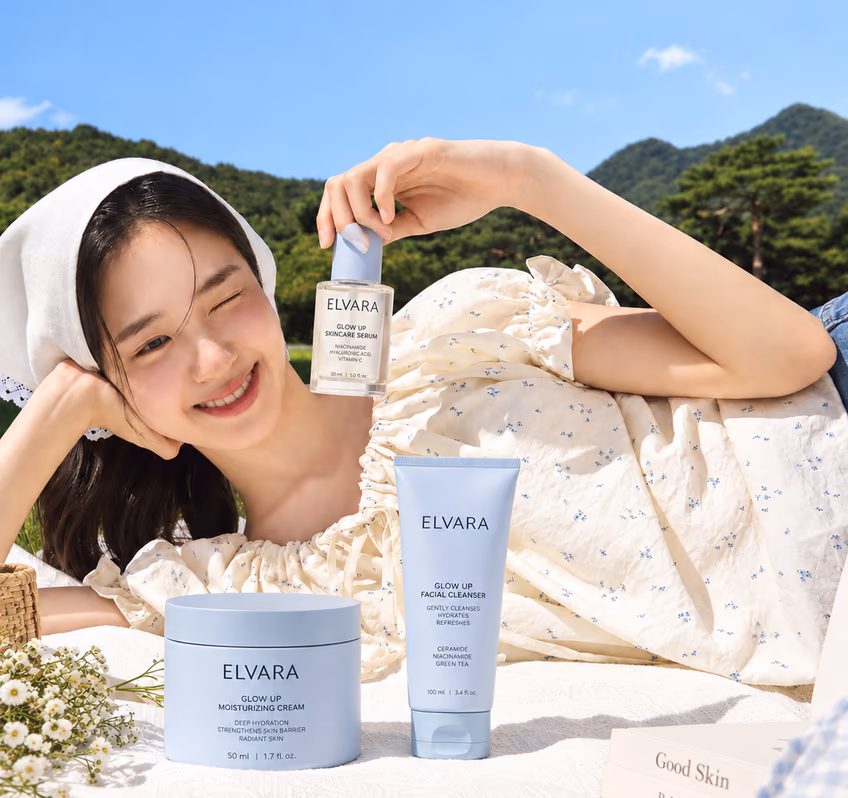 A smiling woman lying in a field with Elvara products beside her